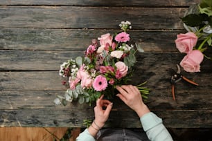 una persona sosteniendo un ramo de flores encima de una mesa de madera
