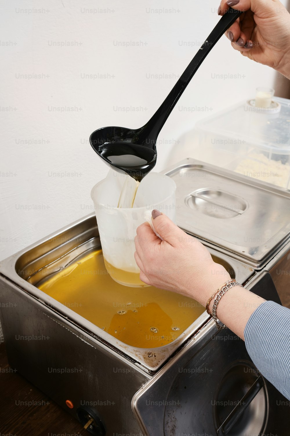 a person pouring liquid into a container with a spoon