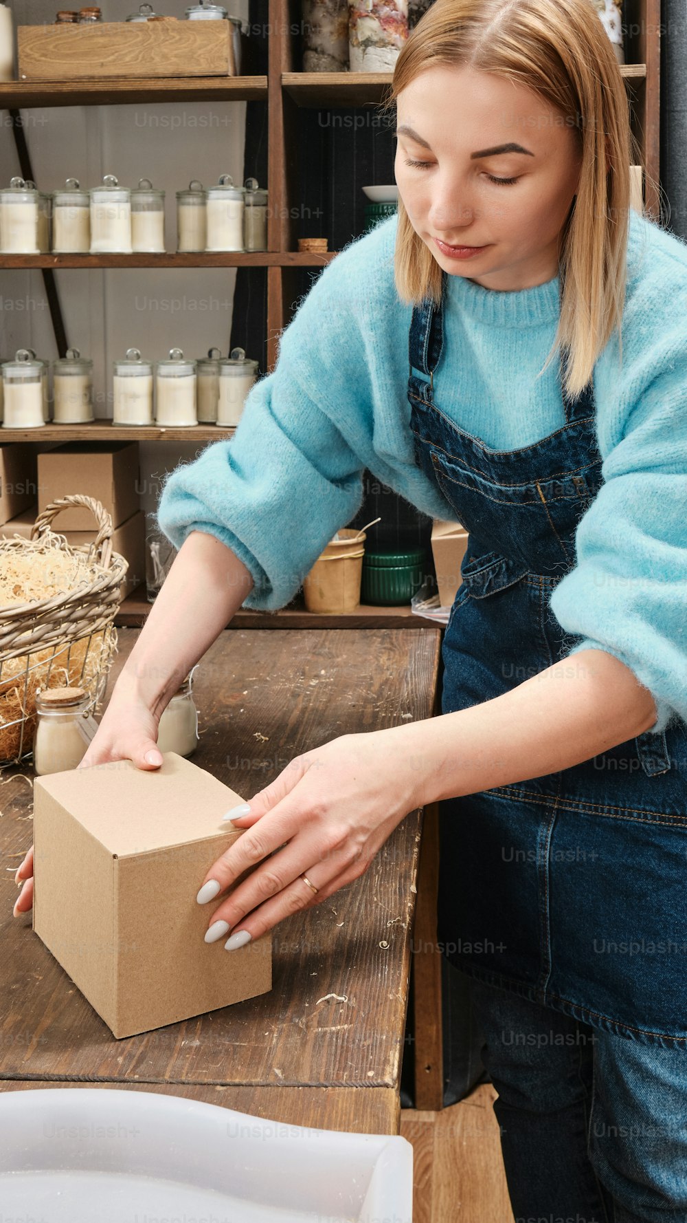 a woman in a blue sweater is putting something in a box