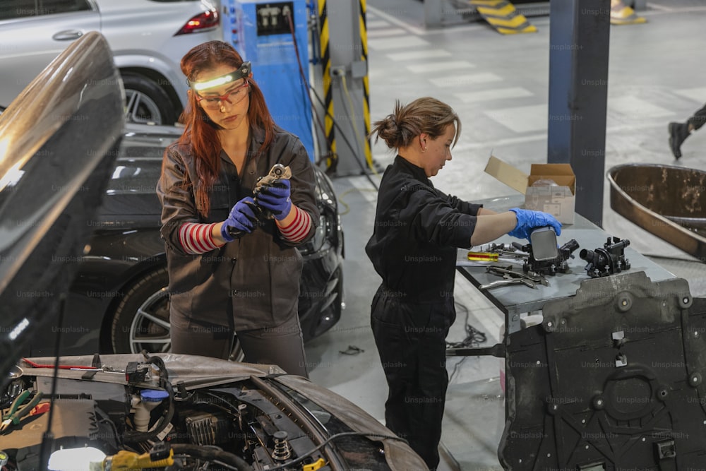 two women working on a car in a garage
