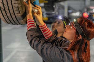two women working on a tire in a garage