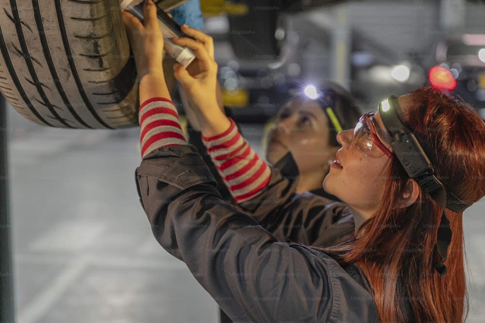 two women working on a tire in a garage