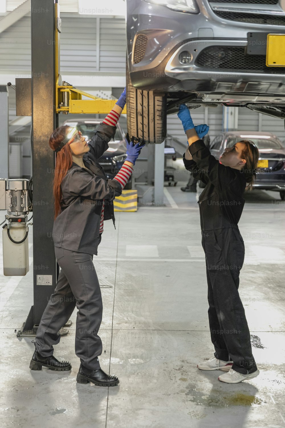 two women working on a car in a garage