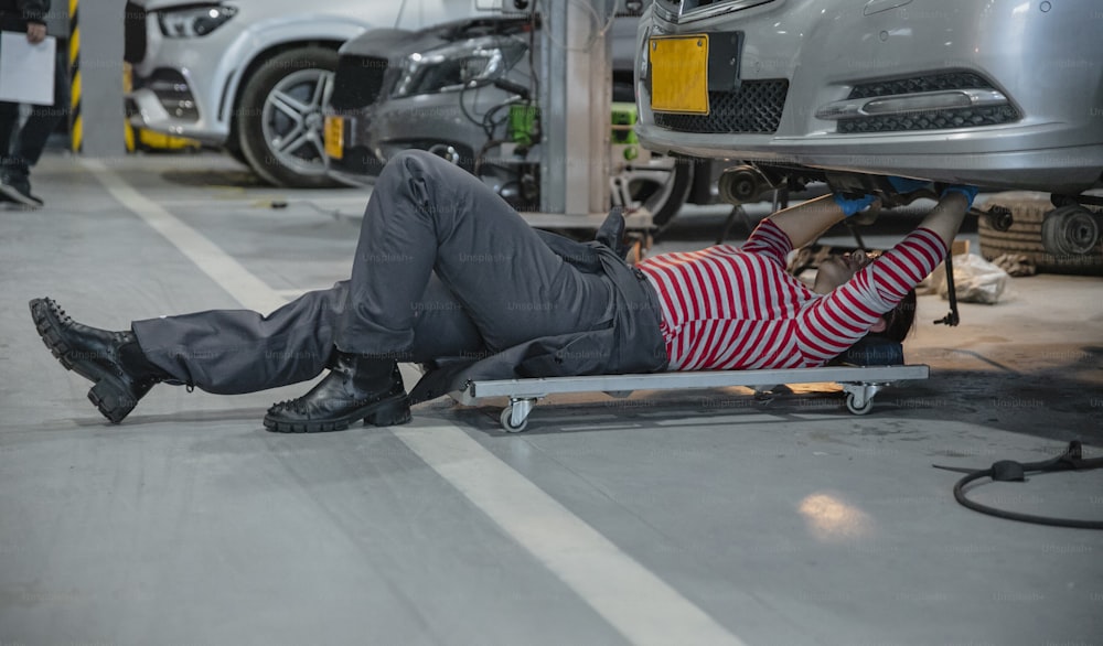 a man laying on the ground in front of a car