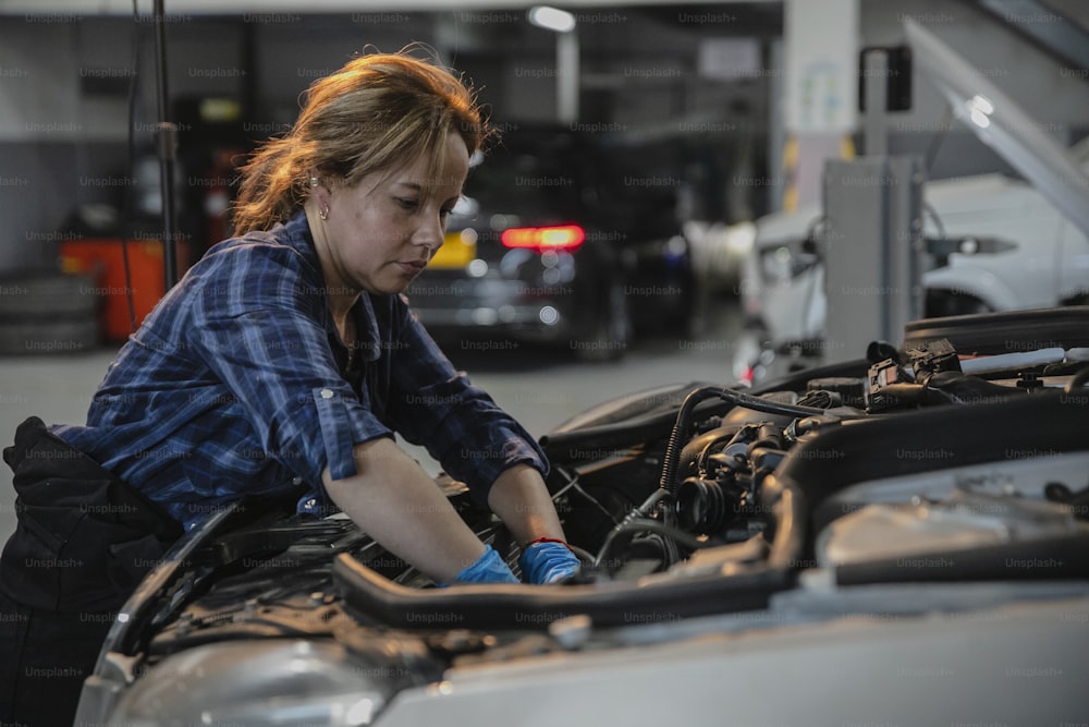 Eine Frau arbeitet an einem Auto in einer Garage