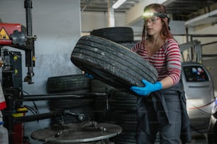 a woman holding a tire in a garage