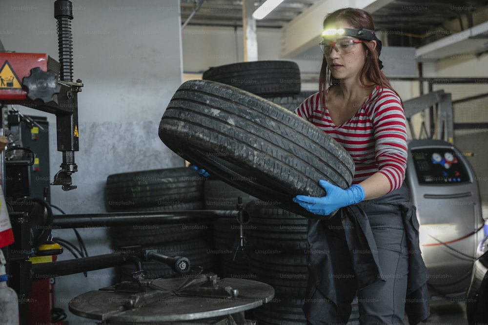 a woman holding a tire in a garage