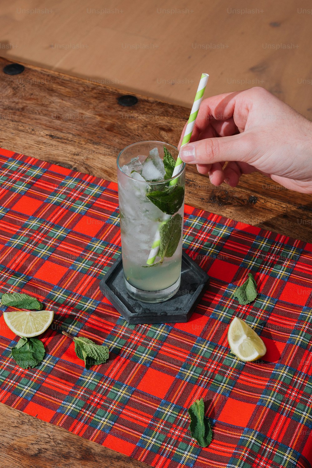 a person holding a green and white straw in a glass