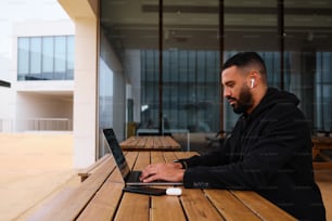 a man sitting at a wooden table using a laptop computer