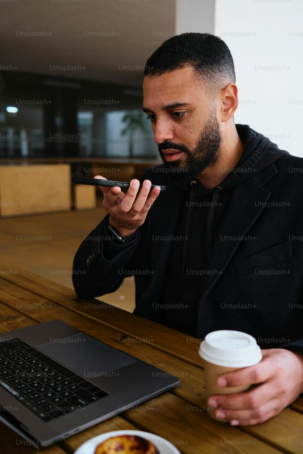 Un hombre sentado en una mesa con una computadora portátil y una taza de café