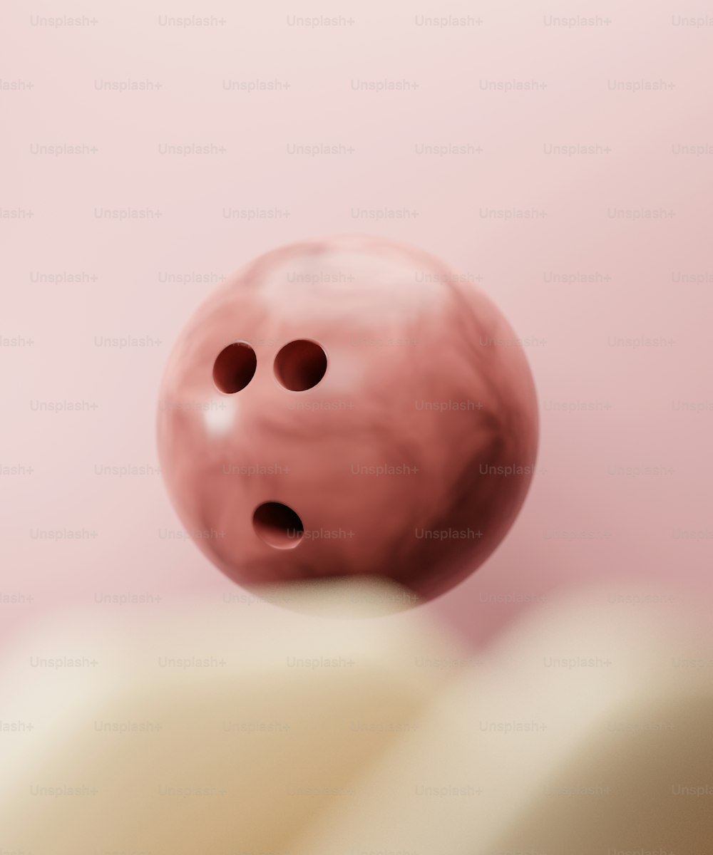 uma bola de boliche rosa com dois orifícios nela