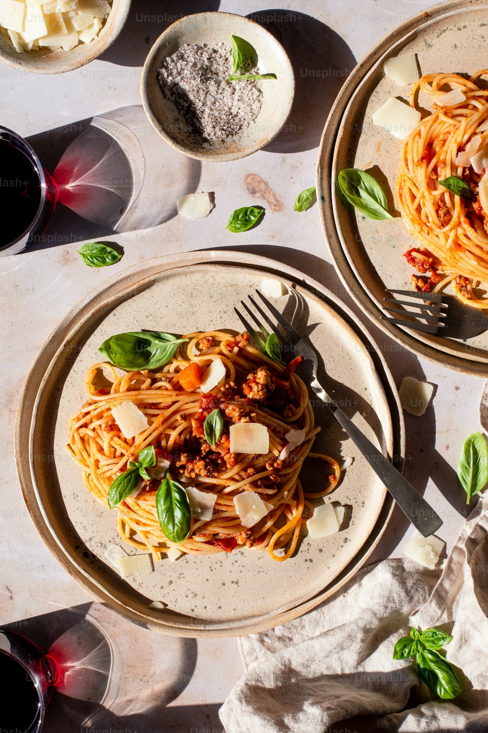 two plates of spaghetti with sauce and cheese