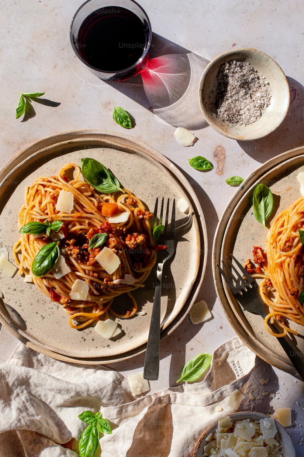 two plates of spaghetti with basil and parmesan cheese
