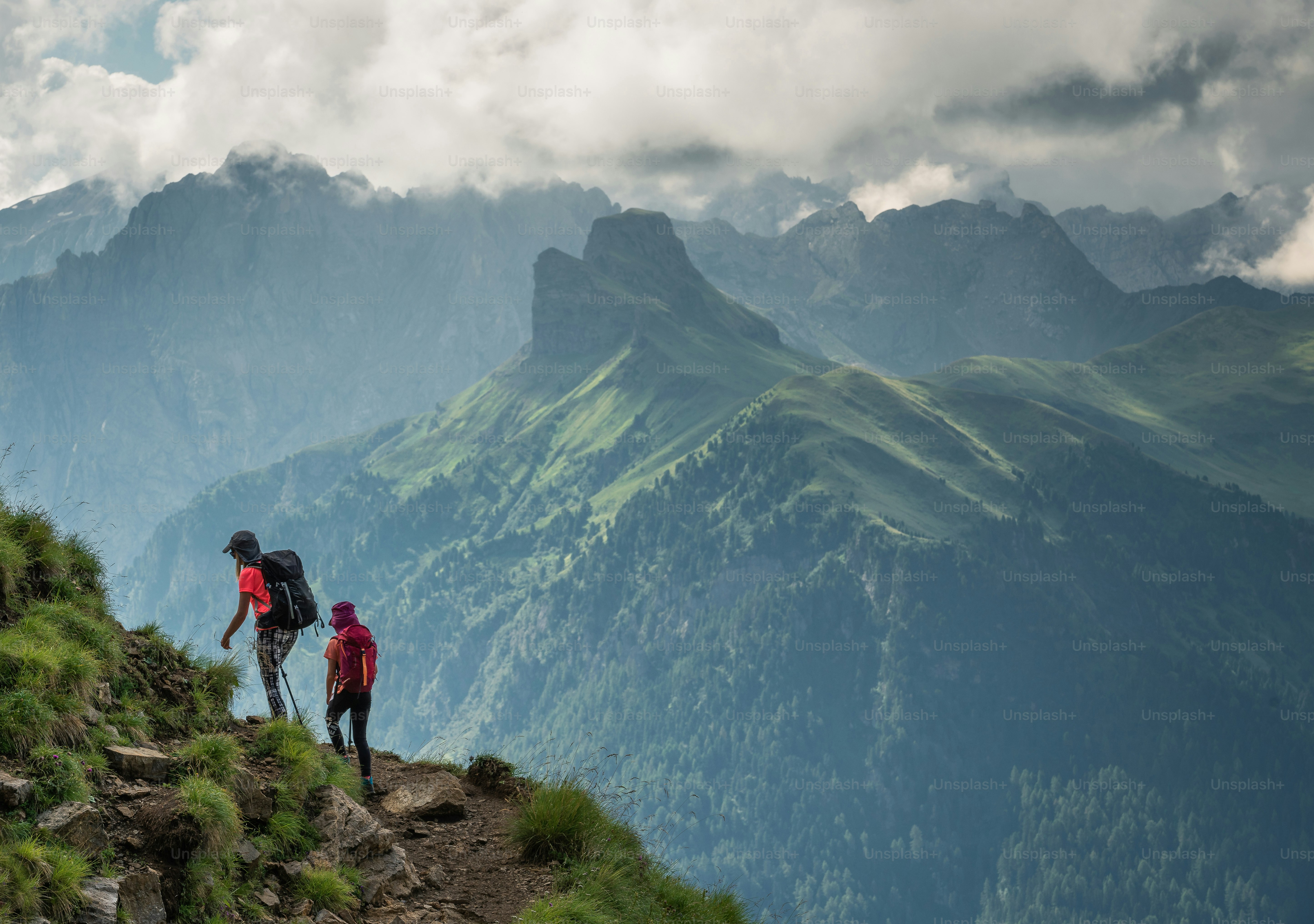 A female hiker and her daughter trekking in the Dolomites mountains in Italy.