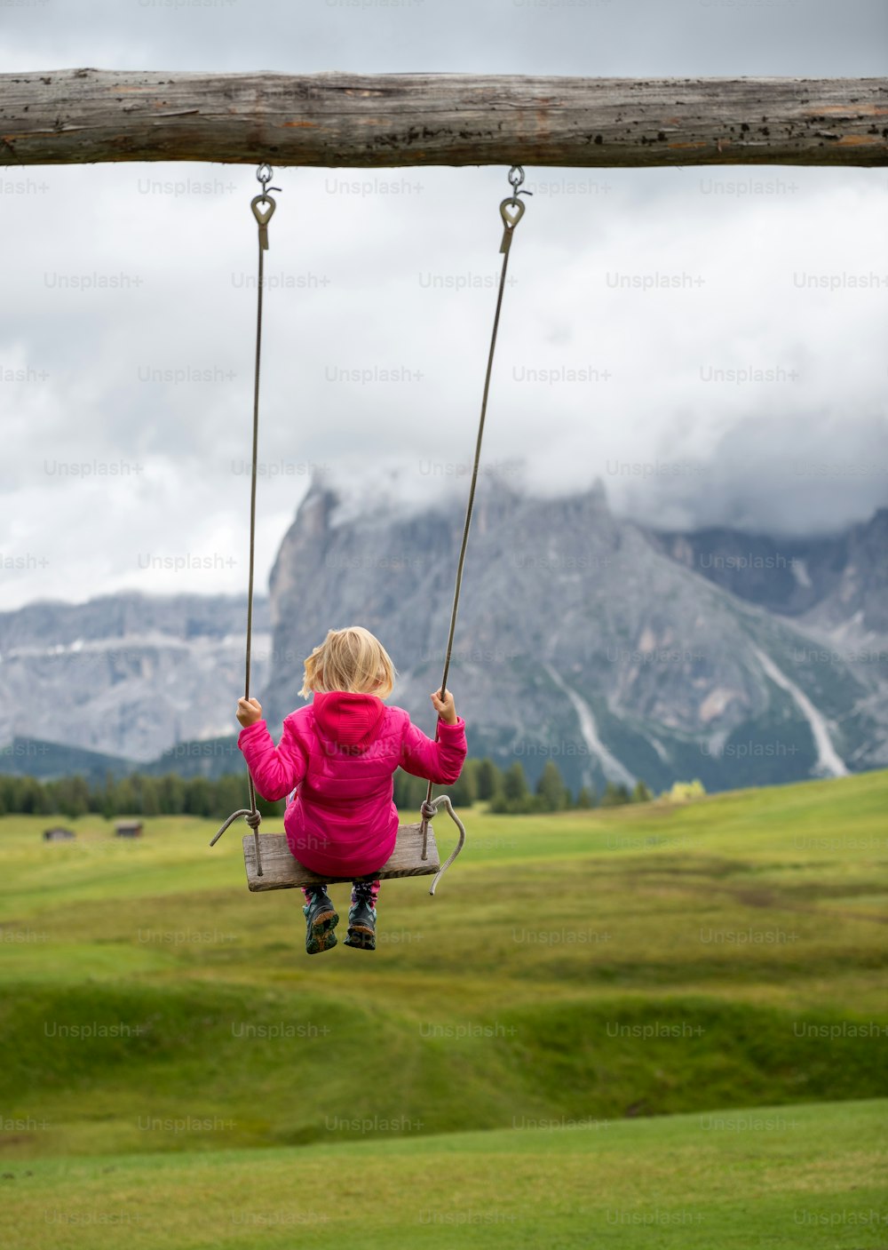 a little girl sitting on a swing in a field