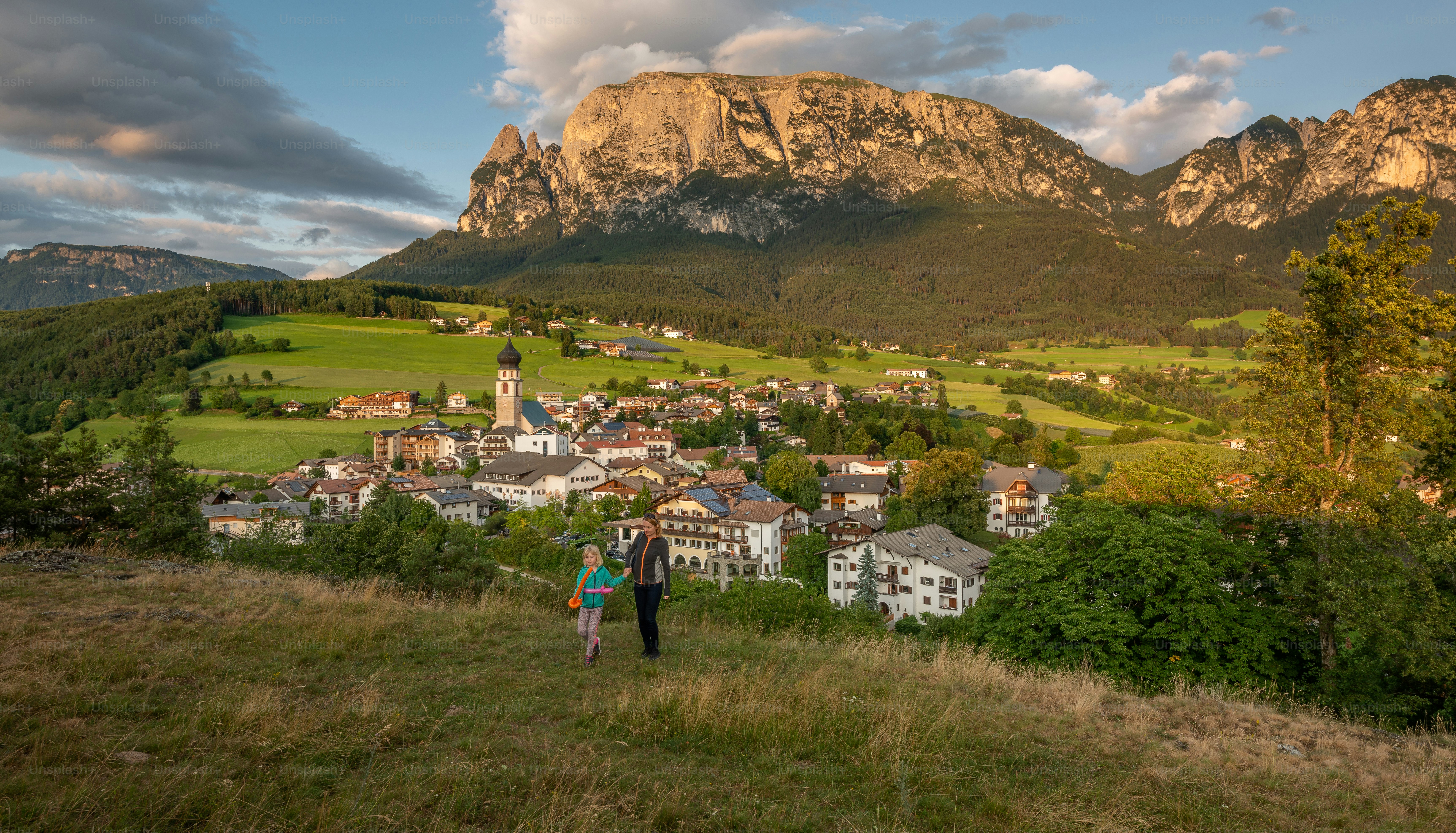 Un par de personas de pie en la cima de una exuberante ladera verde