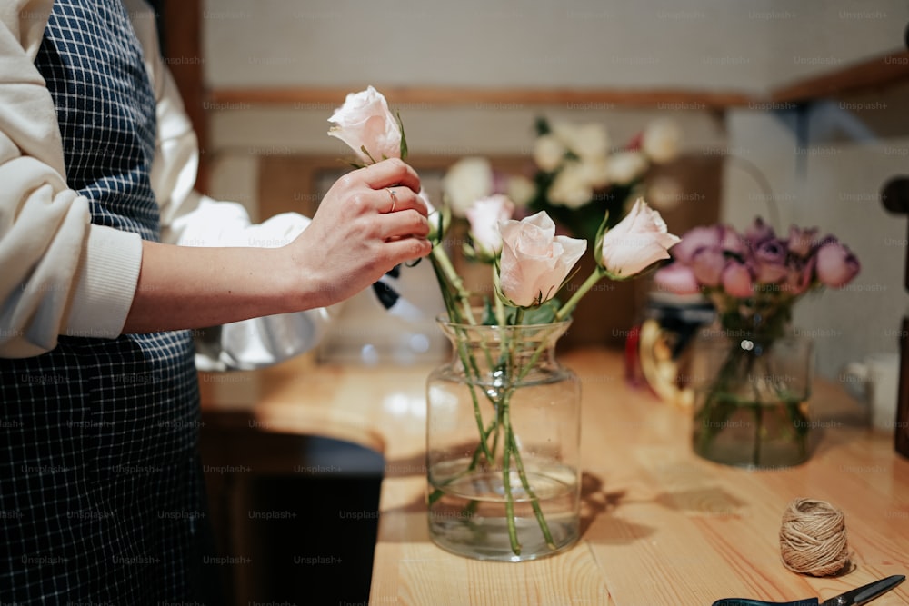 탁자 위의 꽃병에 꽃을 꽂고 있는 여자