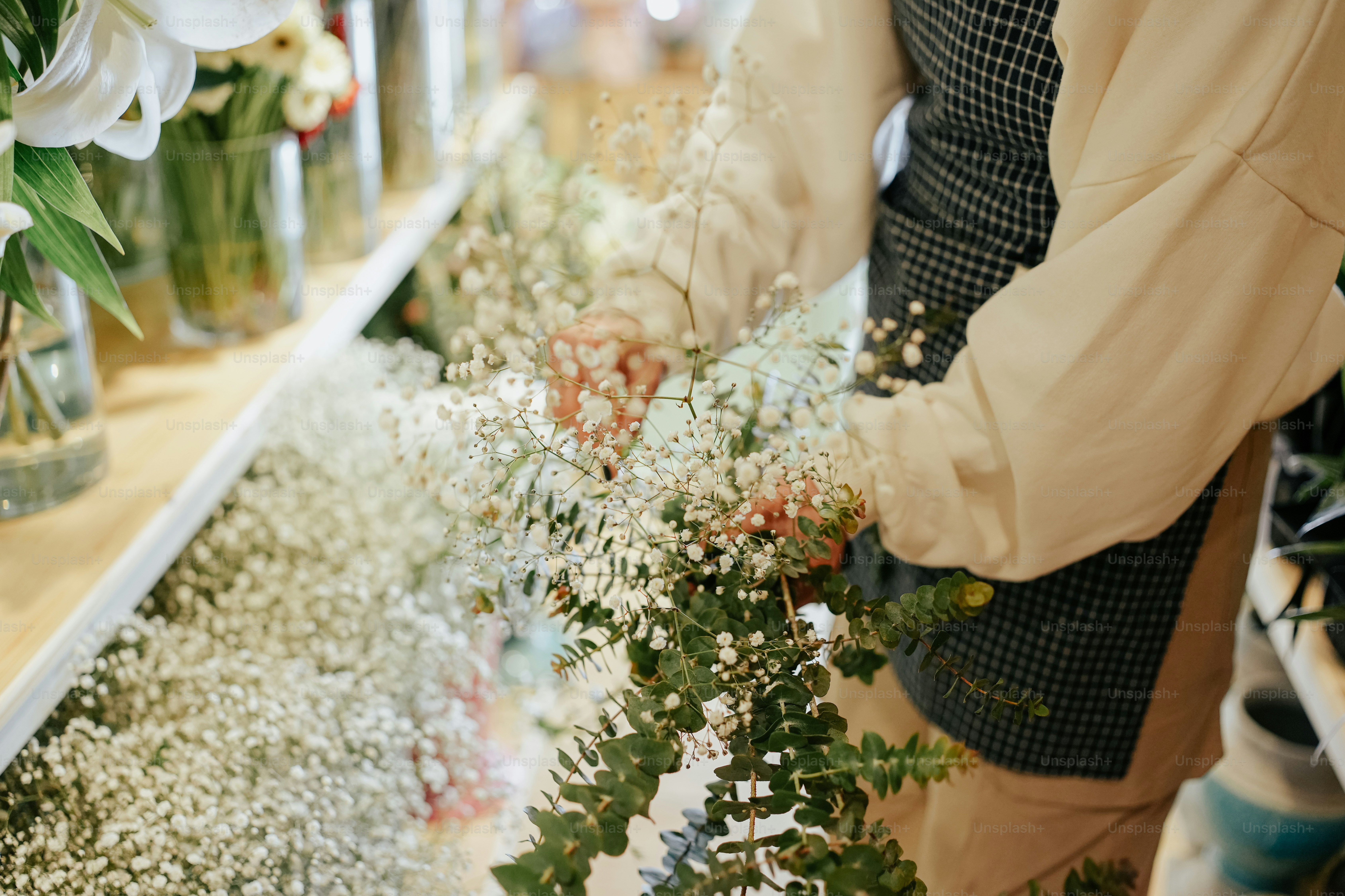 a person arranging flowers in vases on a shelf