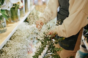 a person arranging flowers in vases on a shelf