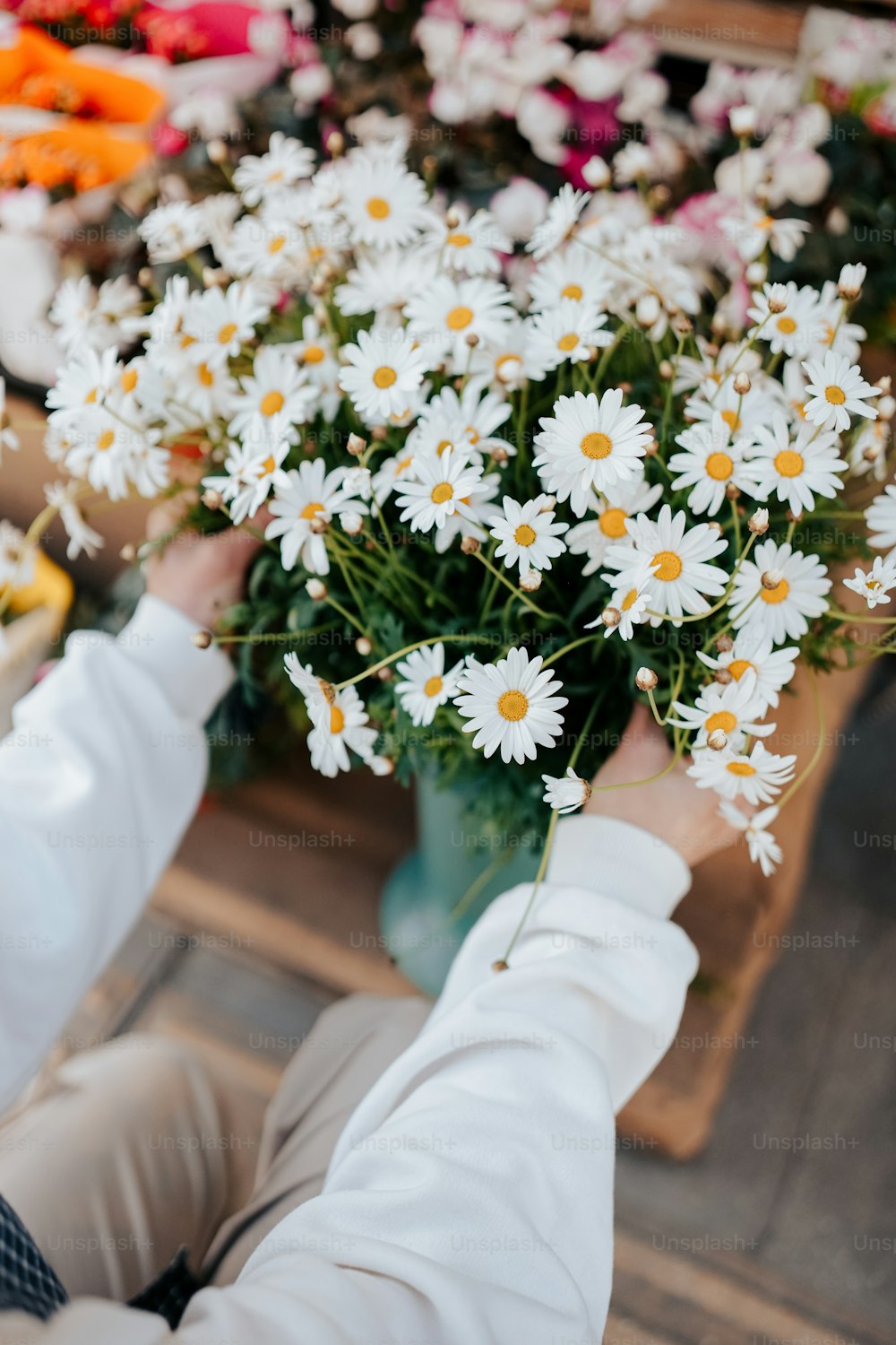 a person holding a vase full of daisies