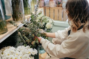 a woman arranging flowers in vases on a shelf