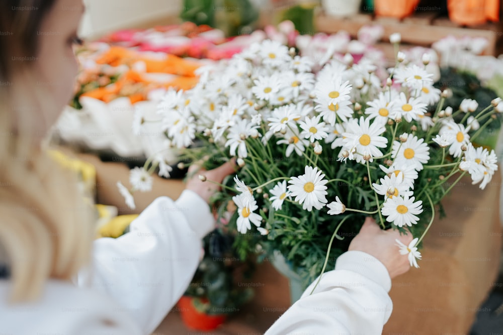 a woman arranging daisies in a flower shop
