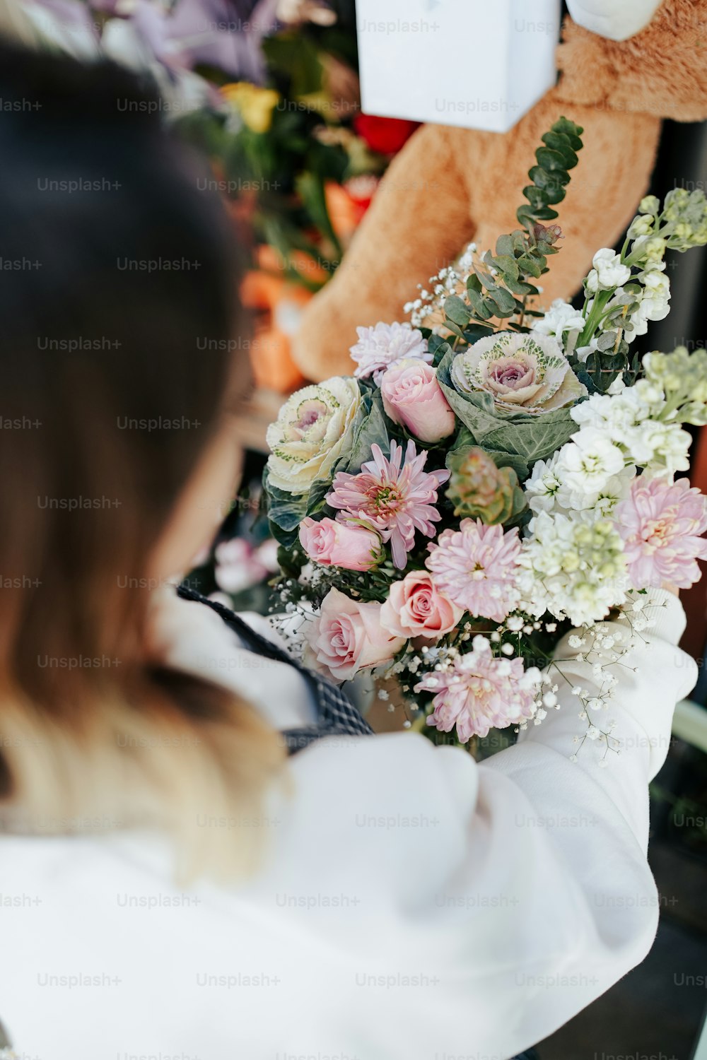 a woman holding a bouquet of flowers in front of a teddy bear