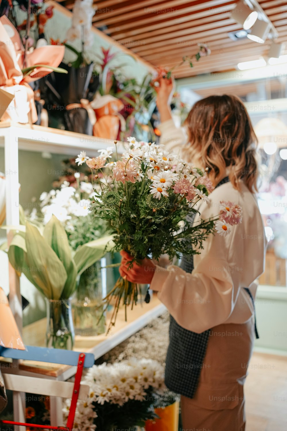 a woman holding a bouquet of flowers in a flower shop