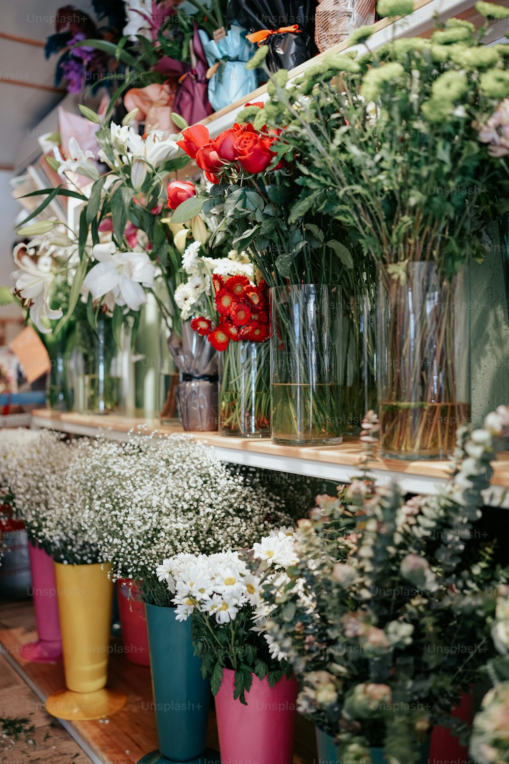 a bunch of vases filled with flowers on a shelf