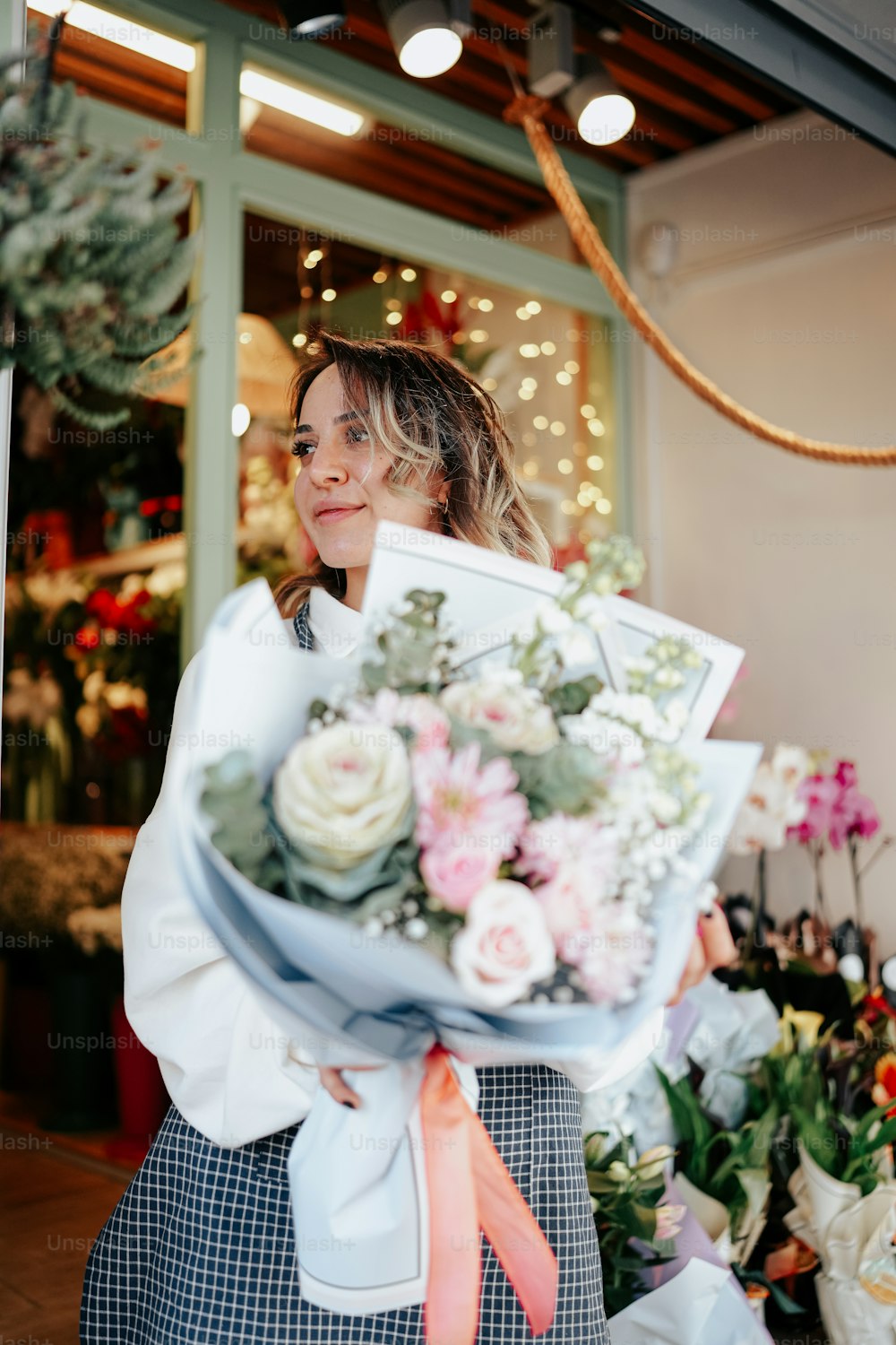 a woman holding a bouquet of flowers in front of a flower shop