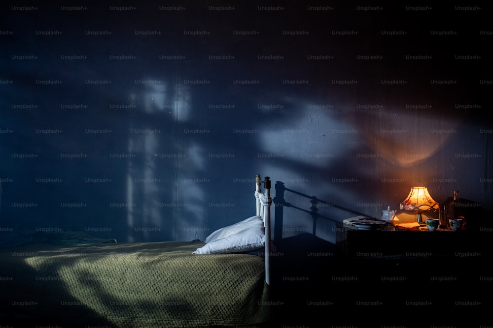 una cama en una habitación oscura con una lámpara al lado