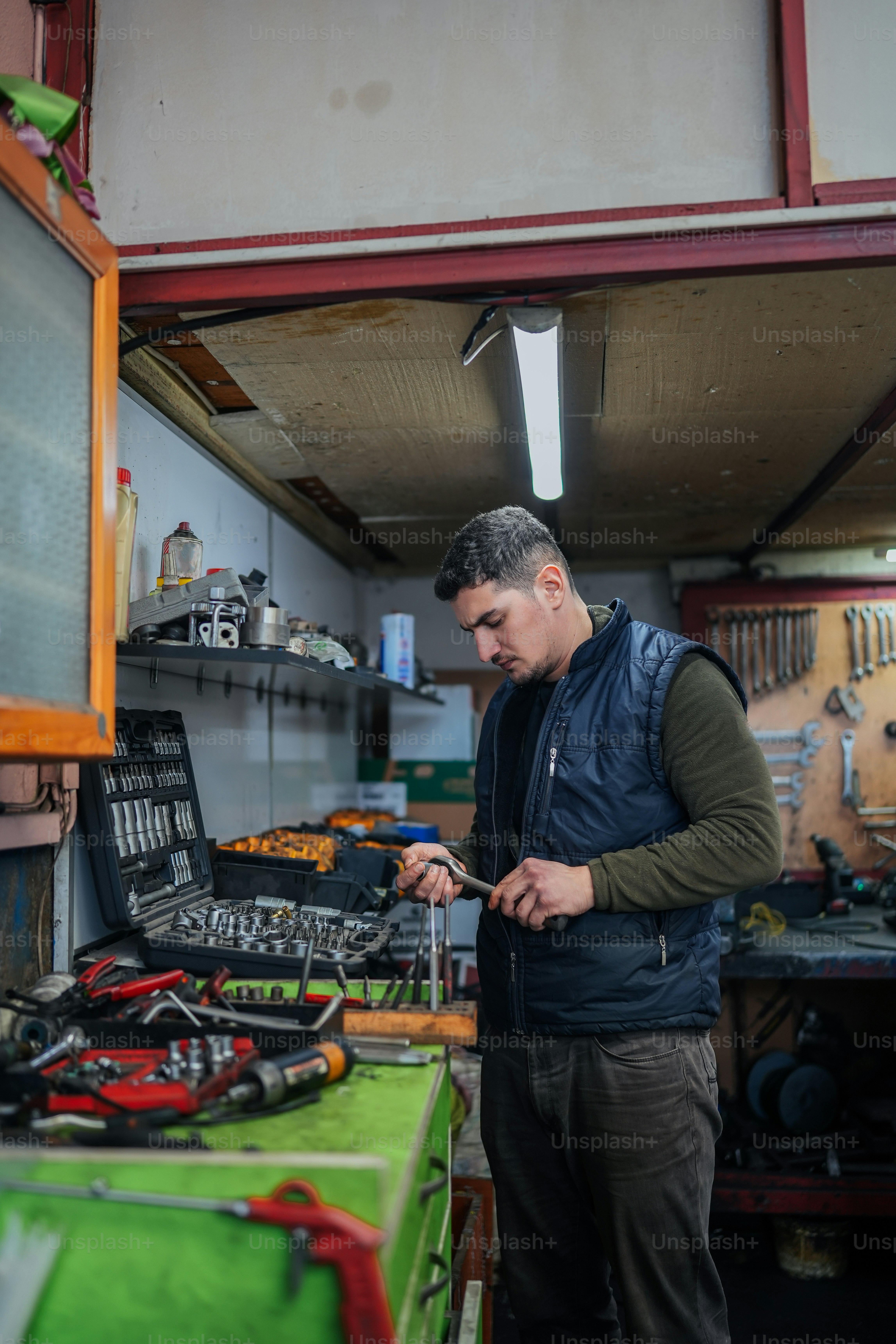 um homem em pé em uma garagem olhando para seu telefone celular