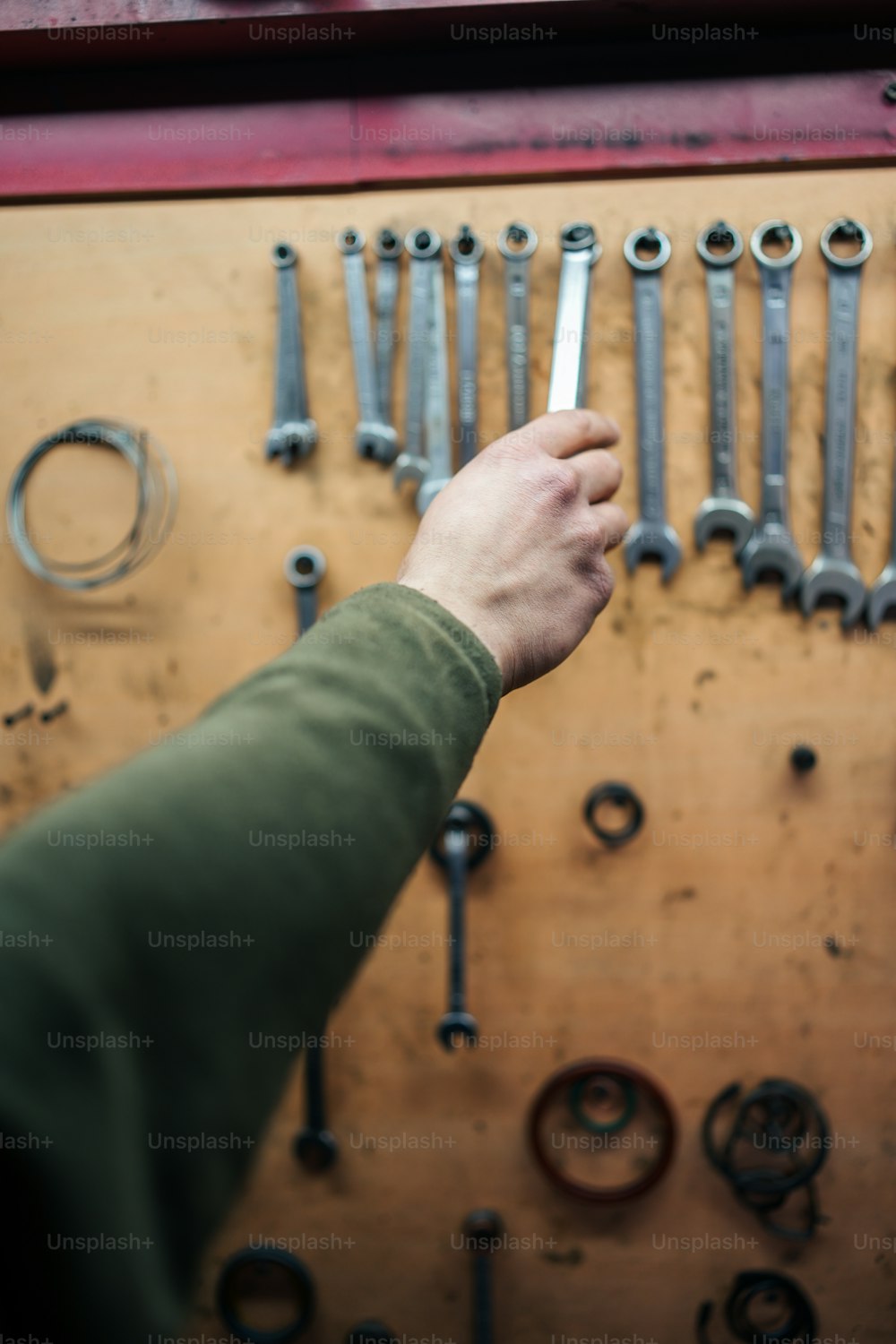 a person holding a wrench in front of a bunch of wrenches