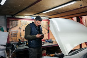 Un homme dans un garage regardant son téléphone portable