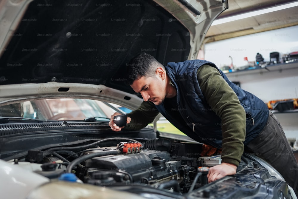 a man working on a car engine in a garage