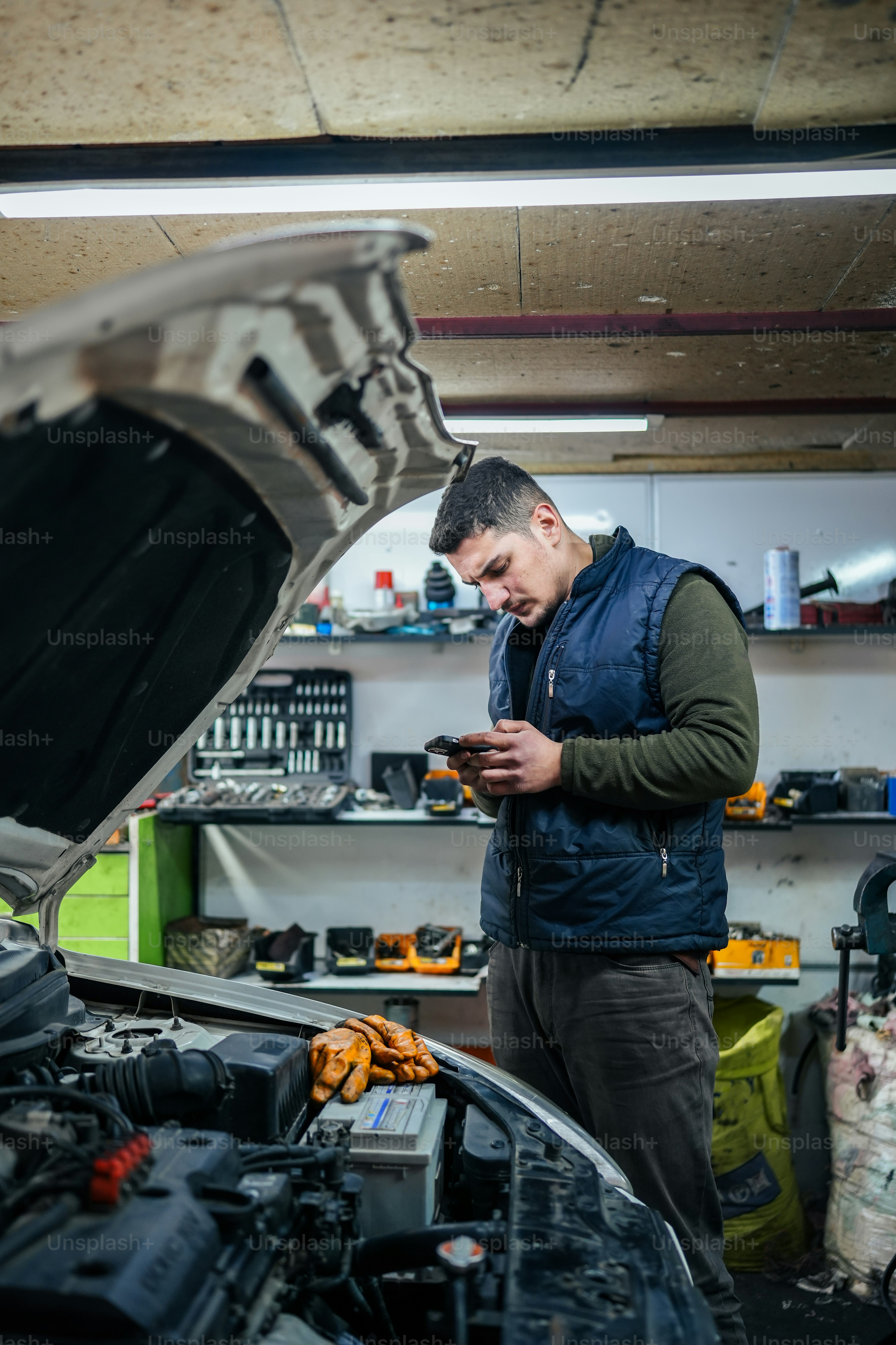 a man looking at his cell phone in front of a car