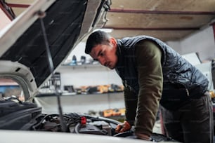 Un uomo che lavora sul motore di un'automobile in un garage