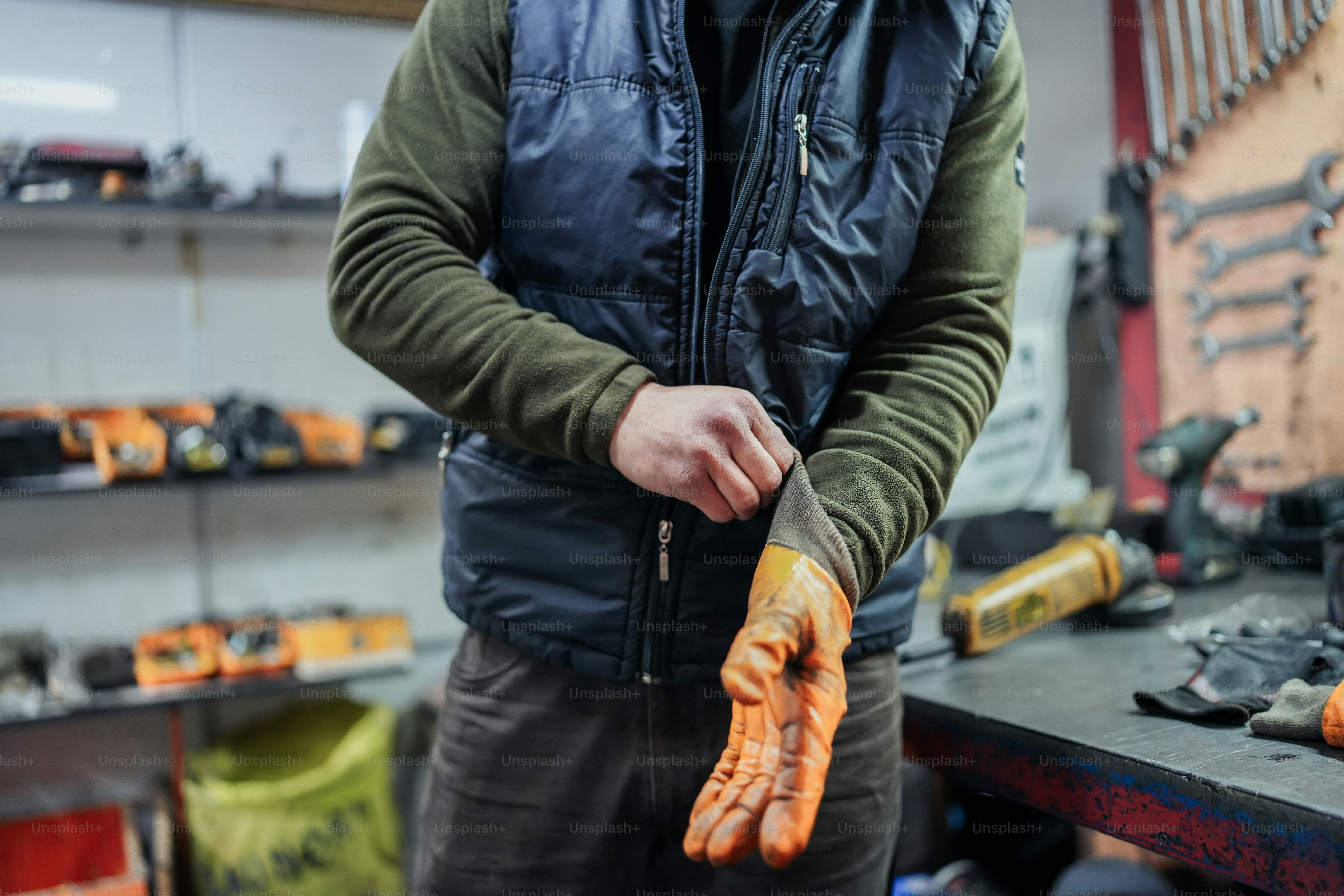Un hombre sosteniendo un par de guantes naranjas