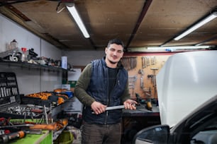 Ein Mann mit einem Schraubenschlüssel in einer Garage