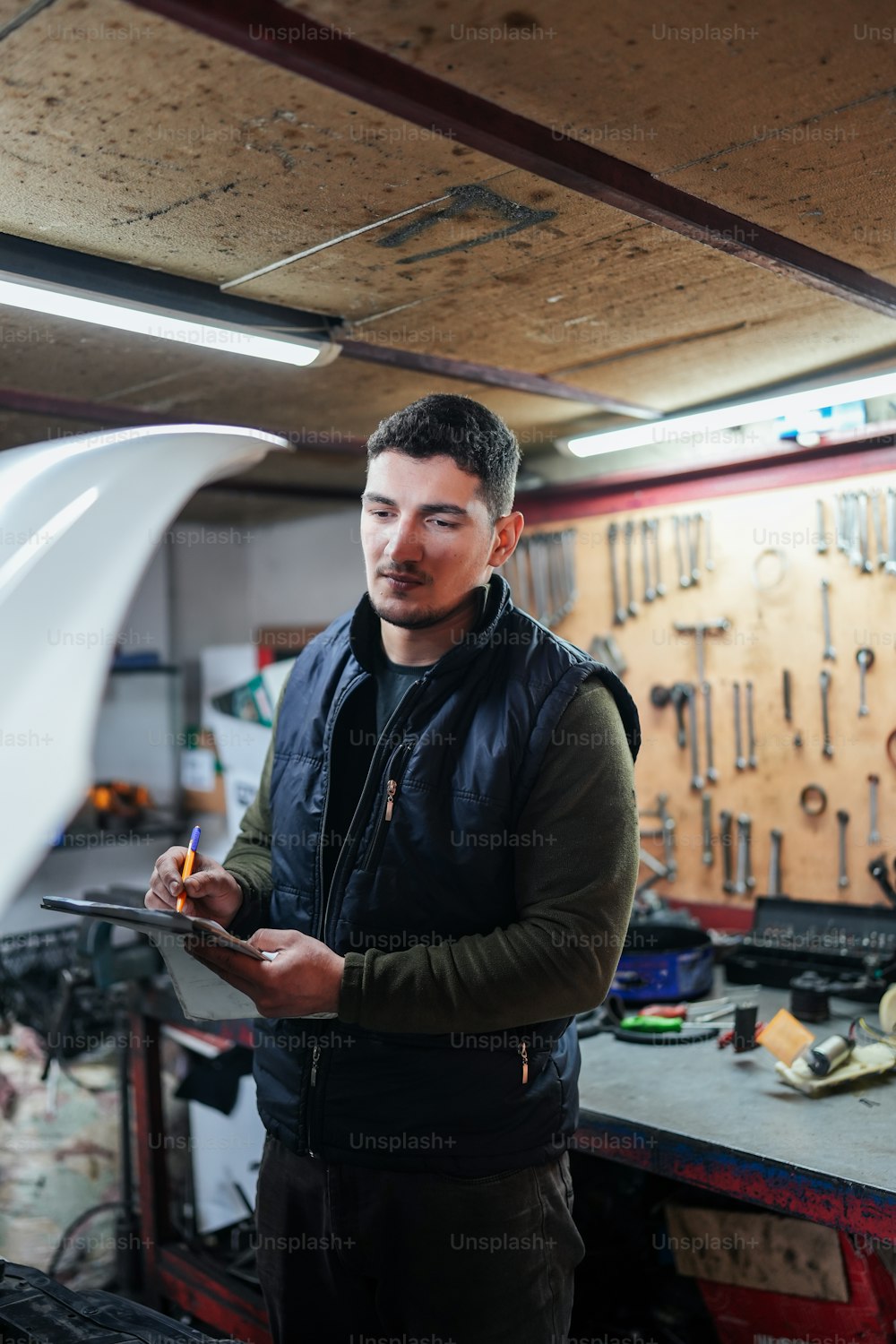 a man in a garage holding a piece of equipment