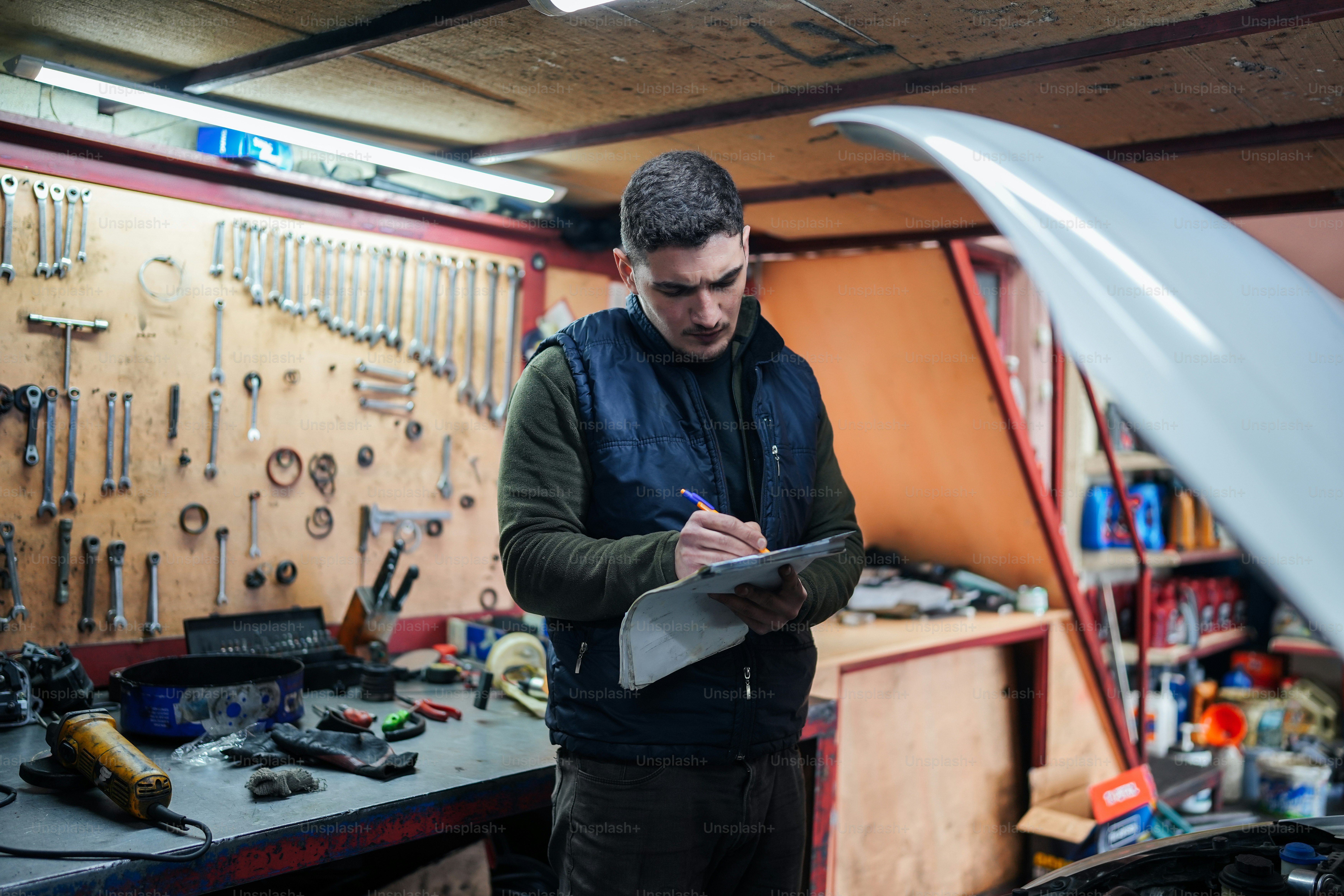 um homem em uma garagem olhando para uma prancheta