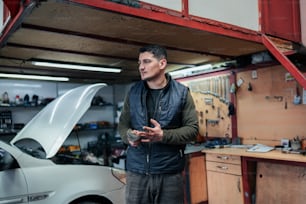 a man standing next to a car in a garage