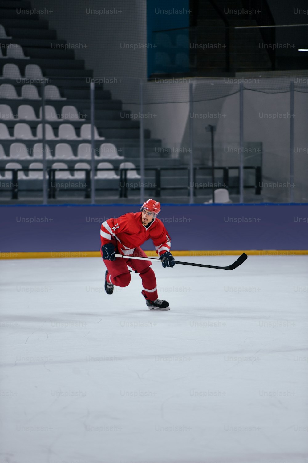 Un homme en uniforme de hockey rouge jouant sur une patinoire