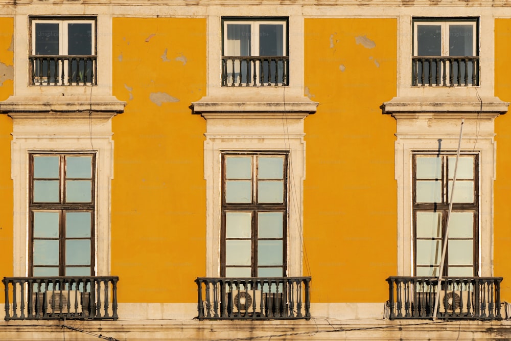 a yellow building with windows and balconies