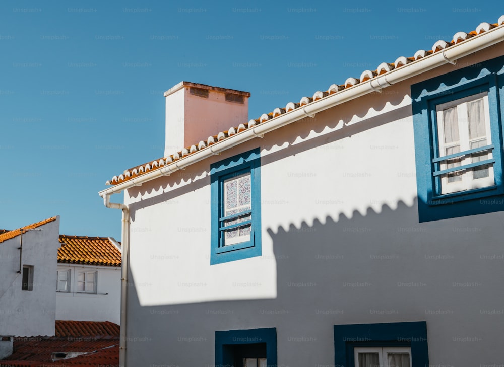 a white house with blue shutters and a red roof