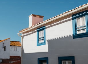 a white house with blue shutters and a red roof