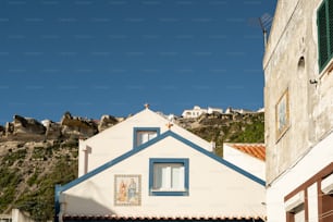 Une maison blanche avec un toit bleu et des fenêtres