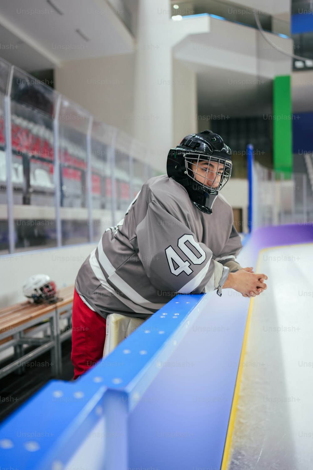 a man in a hockey uniform leaning on a bench