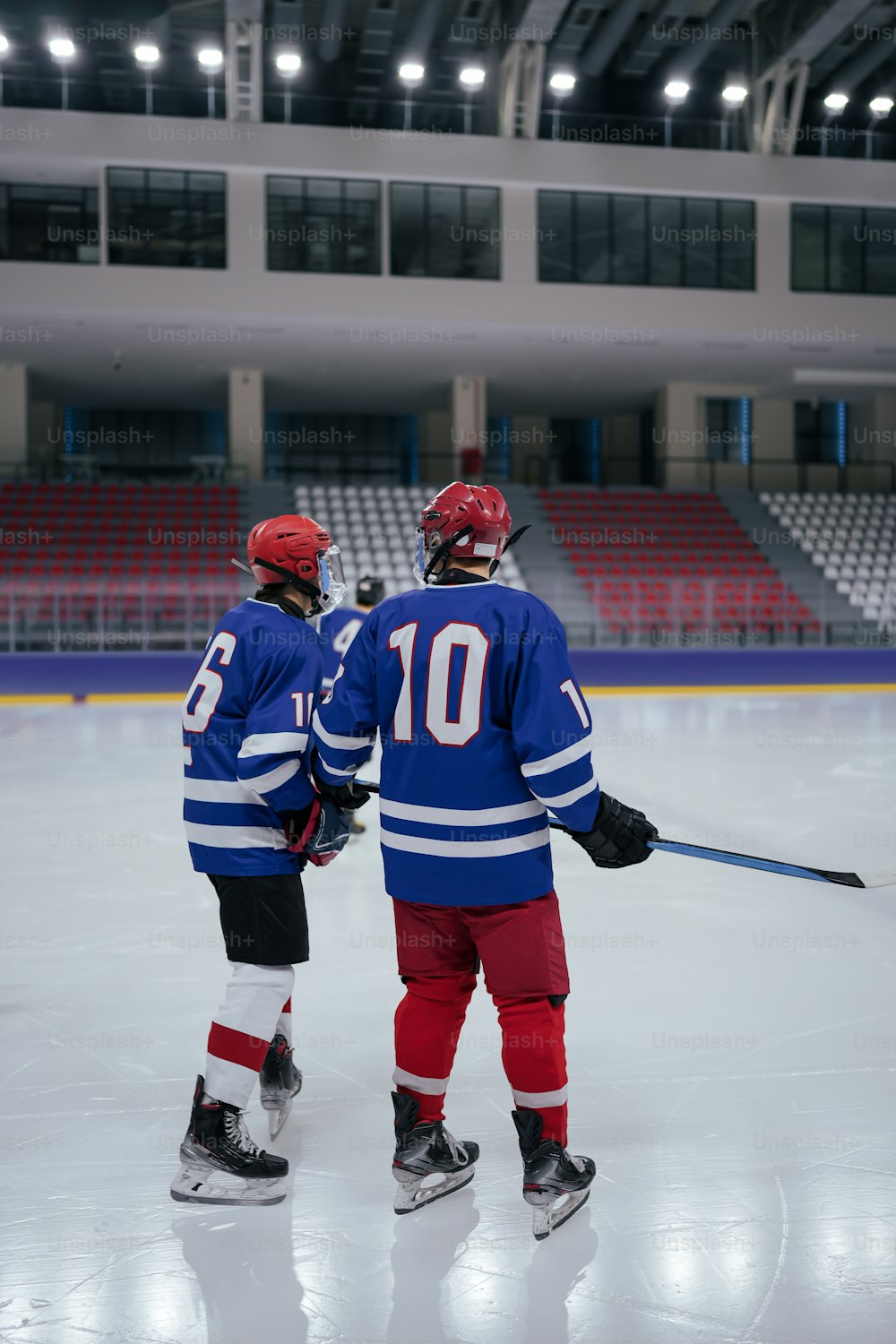 a couple of people standing on top of a ice rink