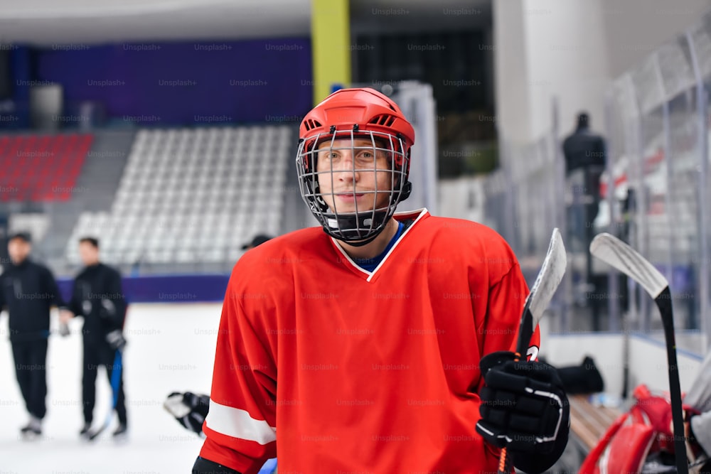 Un hombre con un uniforme rojo de hockey sosteniendo un palo de hockey
